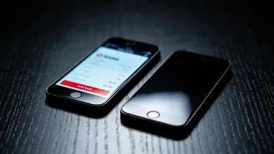 Dois celulares lado a lado sobre mesa escura, um com tela de app bancário iluminada, o outro apagado, mostrando o contraste de visibilidade entre as pessoas do casal.